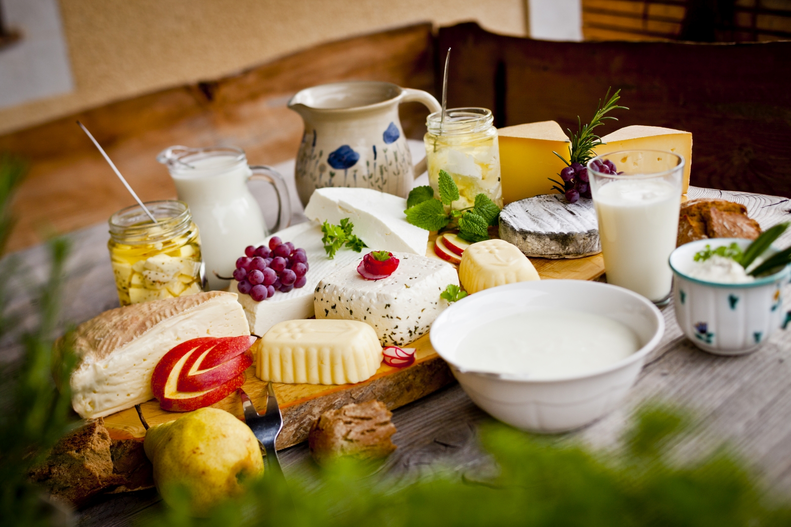 Milch und Milchprodukte auf Brett, in Schüsseln und Krügen auf Holztisch