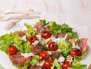 Grüner Salat mit Weißbrotwürfeln, gebratenen Kirschparadeisern und Salami 