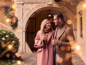 Pärchen mit weihnachtlichen Getränken in einem festlich geschmückten Innenhof