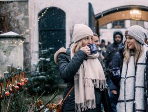Zwei junge Frauen im Freien, weihnachtlich dekoriert, mit Glühweintassen in der Hand