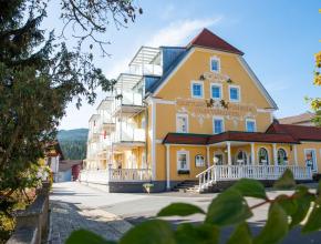 Außenansicht Hotel mit gelber Fassade und Aufschrift Gasthof Pension Prettenhofer