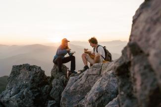 2 junge Wanderer auf Berggipfel beim Essen