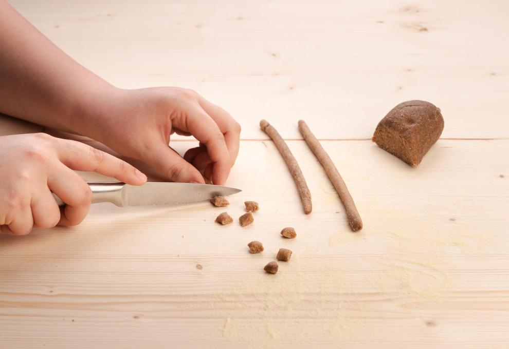 Den Nudelteig zu Strängen formen und kleine Stücke abschneiden