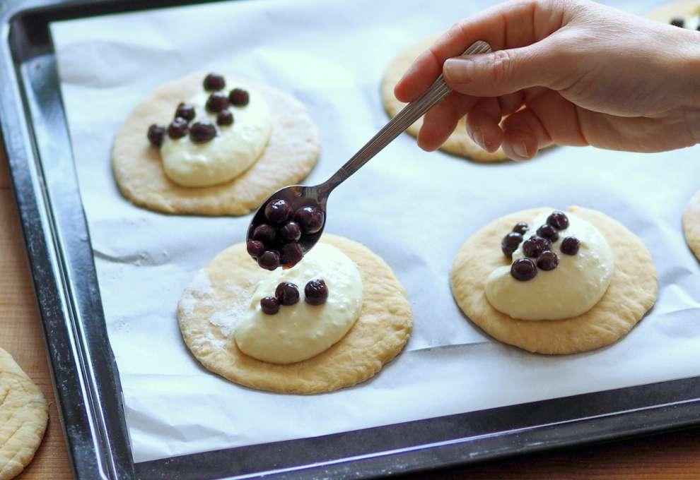 Topfen- und Beerenfülle kommt auf ovale Teigfladen auf Backblech