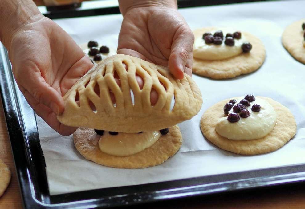 Teigfladen mit Gittermuster kommt auf gefüllte Teigfladen auf Backblech