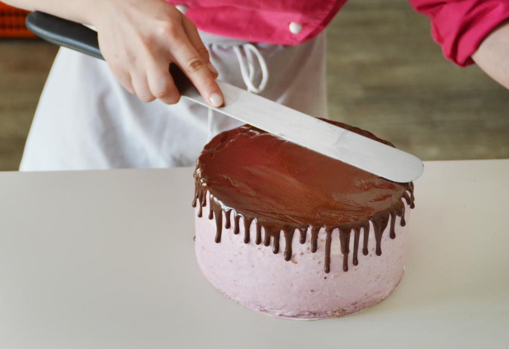 Schokoglasur auf rosa eingstrichene Torte auftragen