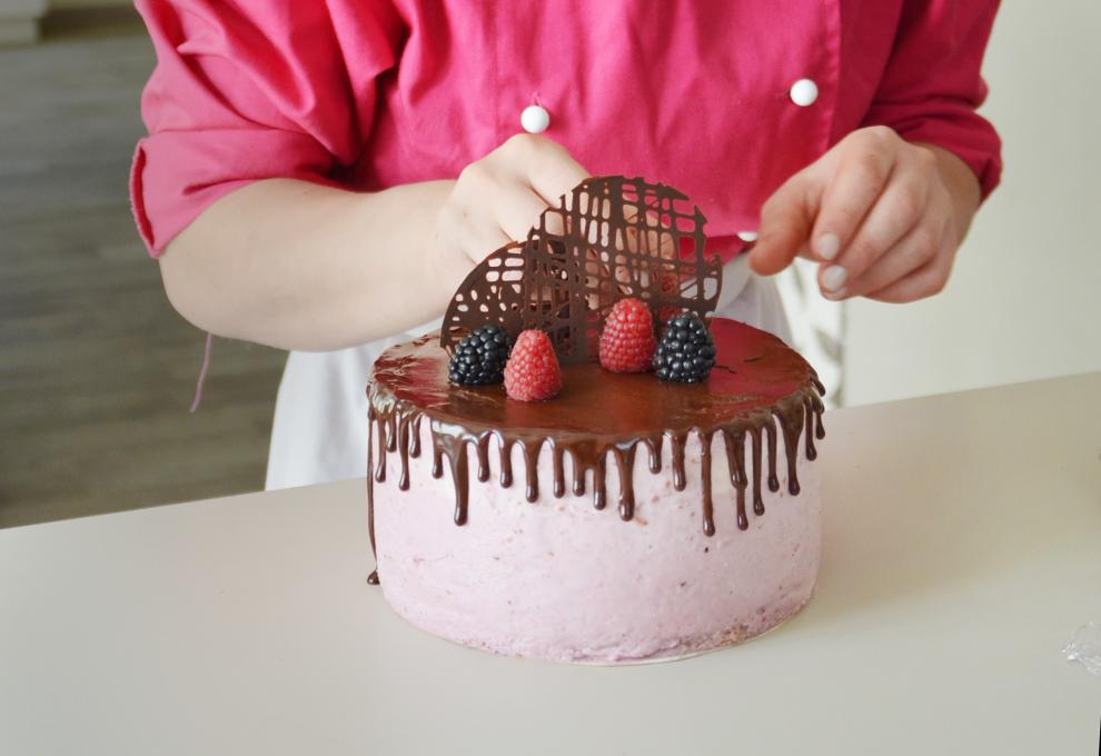 rosa eingestrichene Torte mit Schokoglasur im Drip Cake-Style wird mit Schoko und Beeren dekoriert