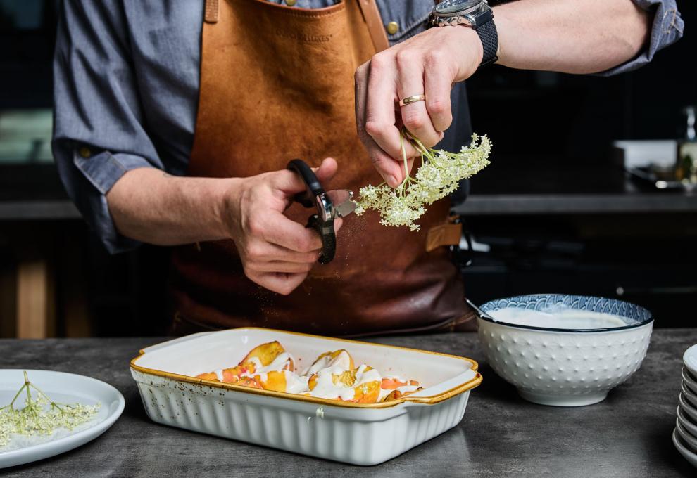 Die Pfirsiche mit Joghurt anrichten und Hollerblüten darüberstreuen