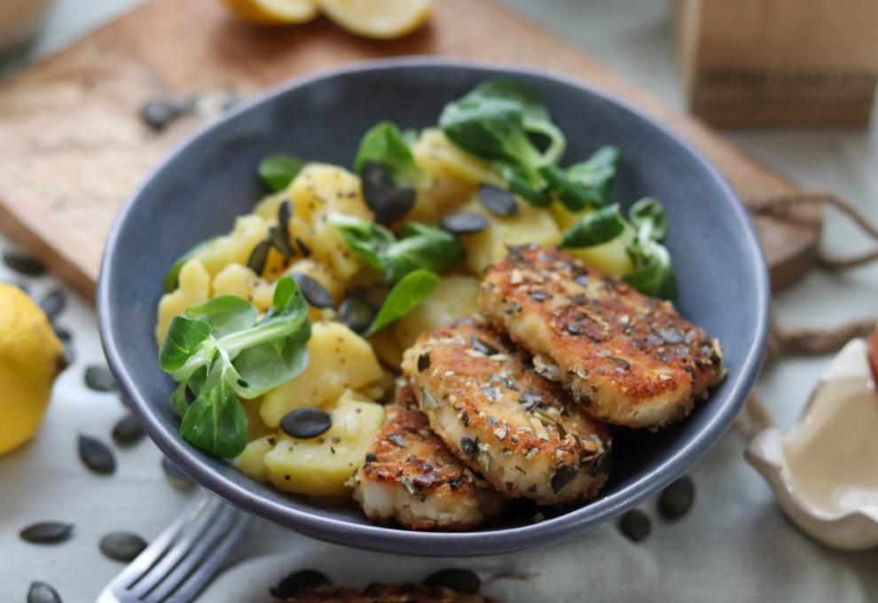 gebackene Halloumischeiben mit Kürbiskernpanade, dazu Erdäpfel-Vogerlsalat, alles in tiefem, blauem Teller
