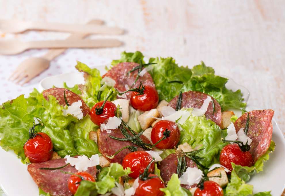 Grüner Salat mit Weißbrotwürfeln, gebratenen Kirschparadeisern und Salami 