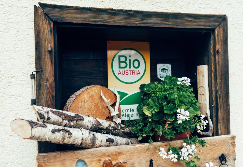 Bio Austria Logo, davor Holz und Blumen