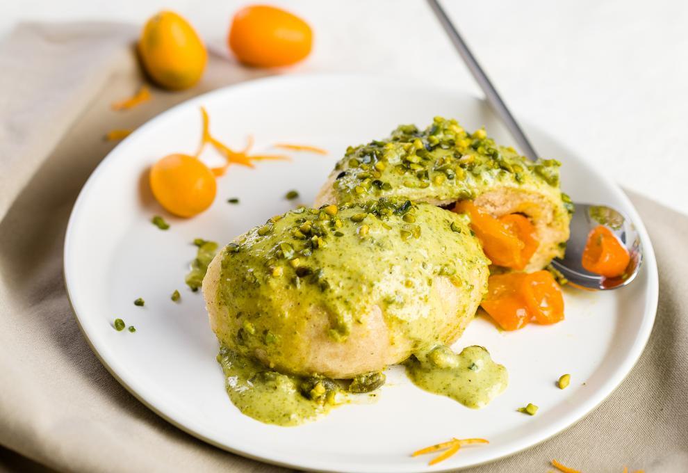 Zwei Germknödel-Hälften mit Pistaziensauce, gefüllt mit Kumquats