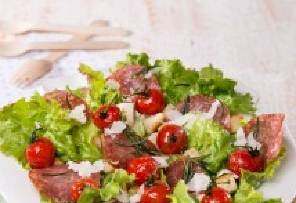 Grüner Salat mit Weißbrotwürfeln, gebratenen Kirschparadeisern und Salami