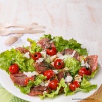 Grüner Salat mit Weißbrotwürfeln, gebratenen Kirschparadeisern und Salami